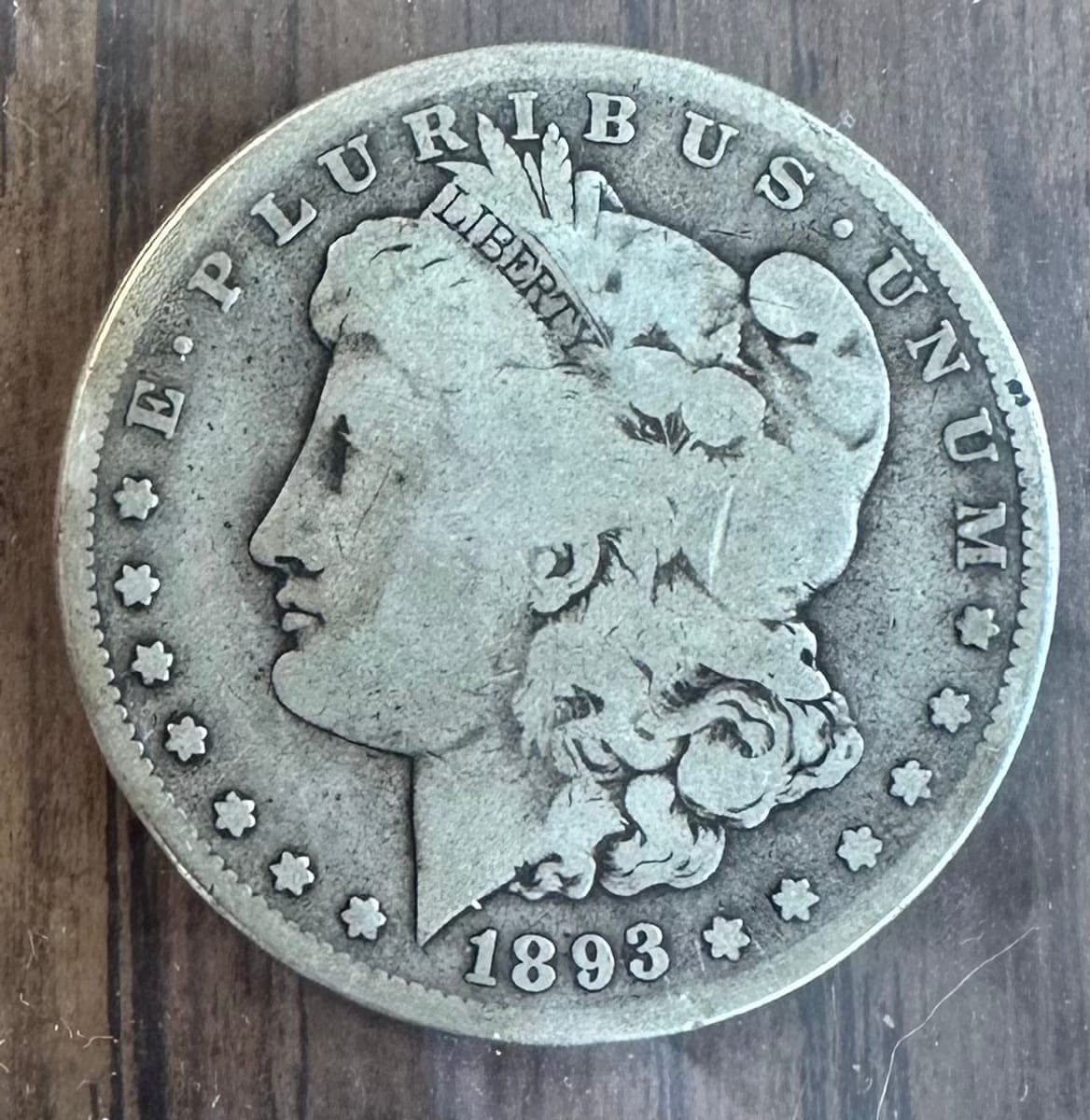 Phone photo of an 1893-S Morgan dollar on a wooden desk